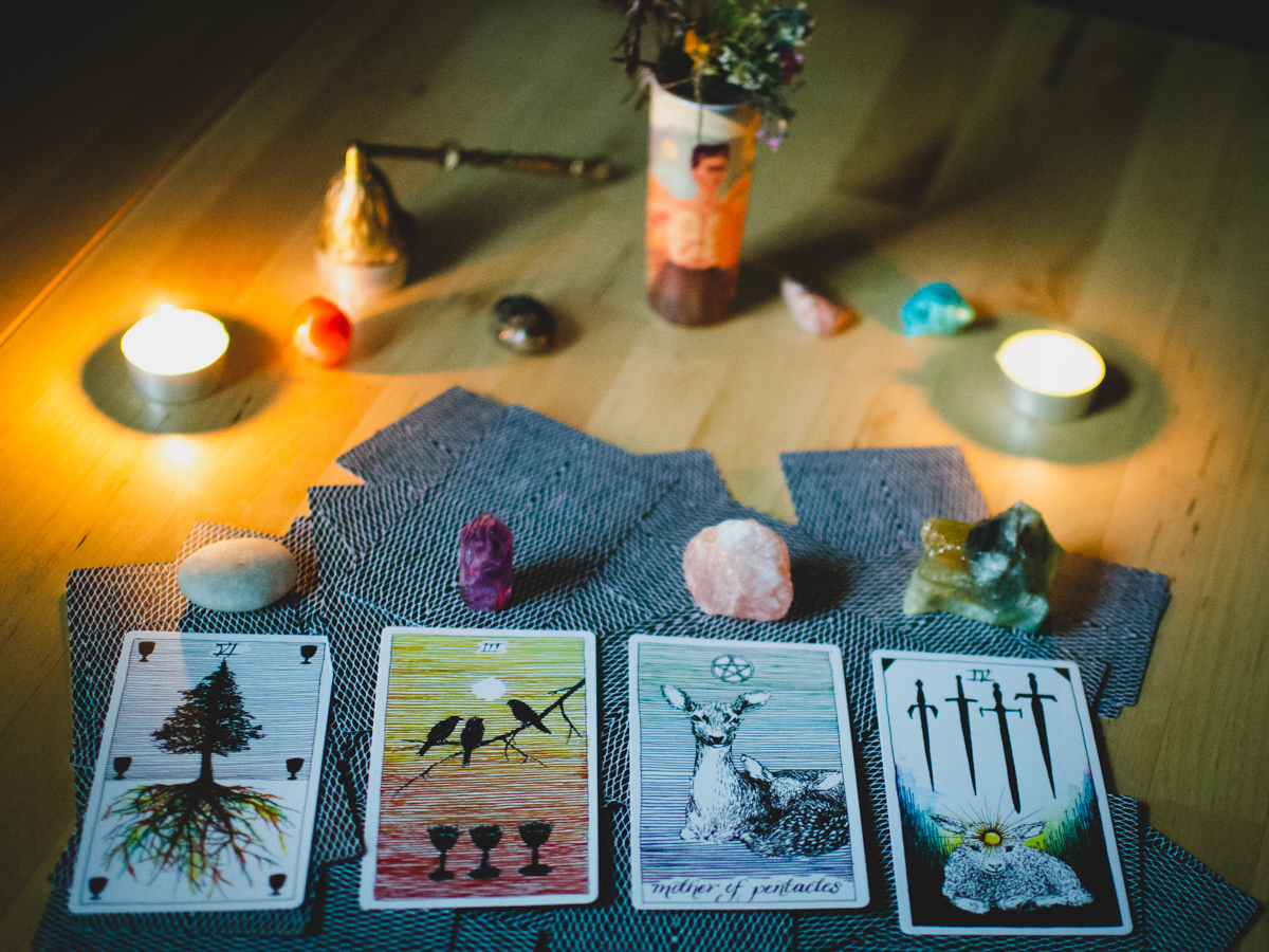 Four-card tarot spread with candles and crystals in the background. Wild Unknown tarot deck.